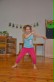 Ein Mädchen ist mittig im Bild zu sehen, sie tanzt, die Beine stehen schulterbreit, die Arme sind in Bewegung.