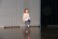 Ein Mädchen tanzt alleine auf der Bühne und hält ein Knie hoch.
