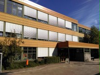 Blick auf den Eingang und eine Fensterfront der Primarstufe vom Schulhof aus bei schönem Wetter.